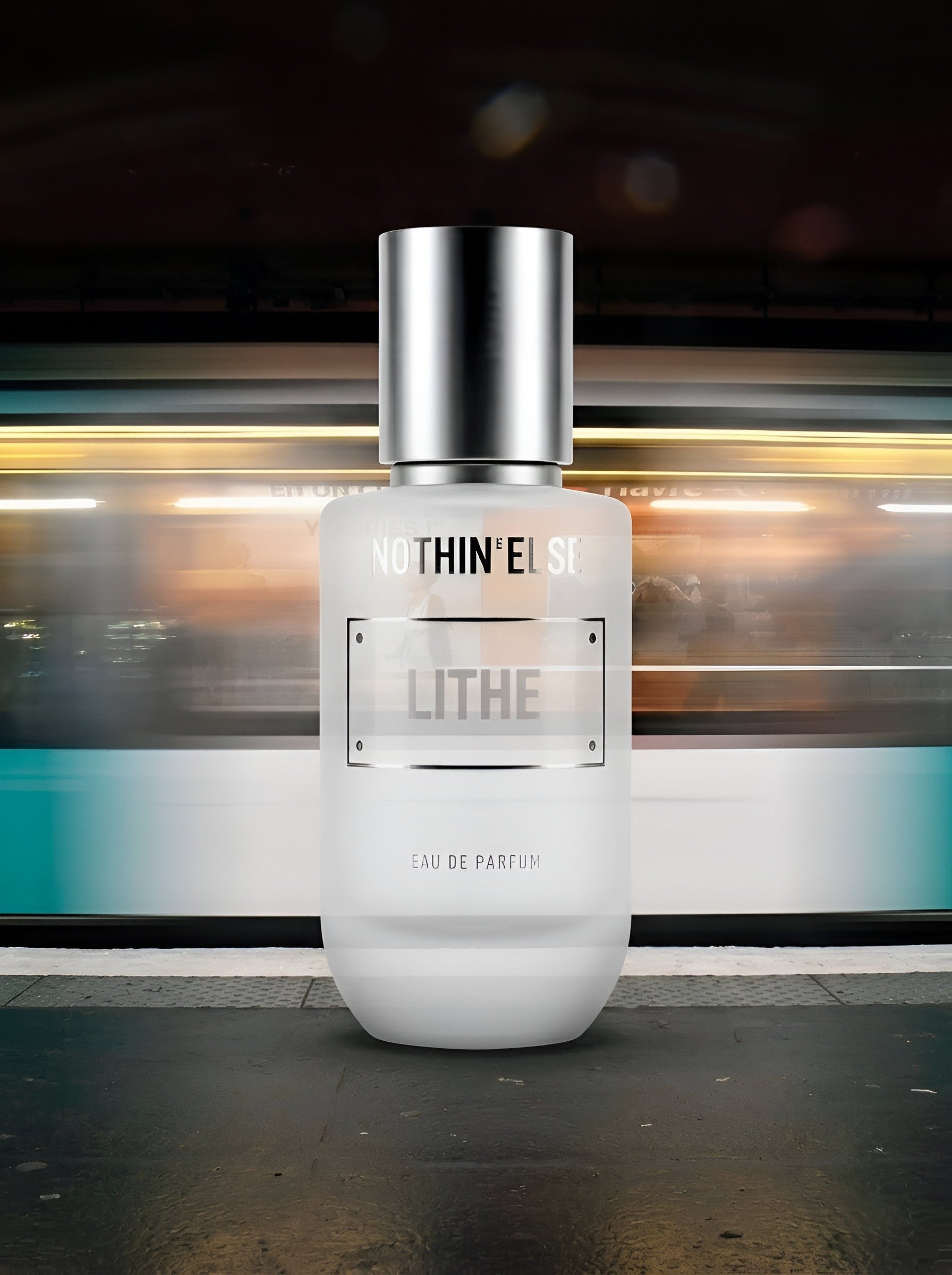 Perfume bottle labeled 'LITHE' by 'NUTHIN' ELSE' on a blurred train platform background